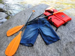 Wet cotton shorts unsuitable for whitewater rafting discarded next to appropriate synthetic gear by a river.