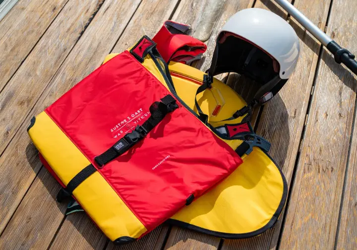 Essential whitewater rafting safety gear: a PFD (life jacket) and helmet displayed clearly in natural daylight.