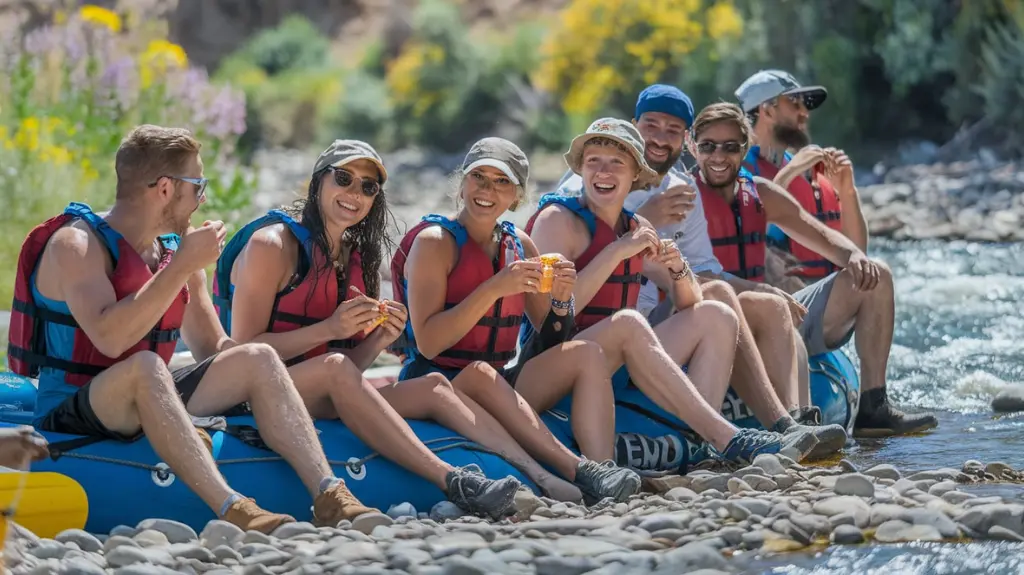 Group of rafters relaxing on the Kern Riverbank, enjoying snacks and scenic views during their adventure.  