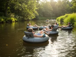 Group of adults enjoying a relaxing river float on stylish tubes with cup holders, surrounded by lush greenery and clear blue skies.