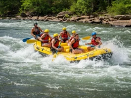 Group of adventurers whitewater rafting on the Chattahoochee River in Columbus, GA, with the city skyline in the background.