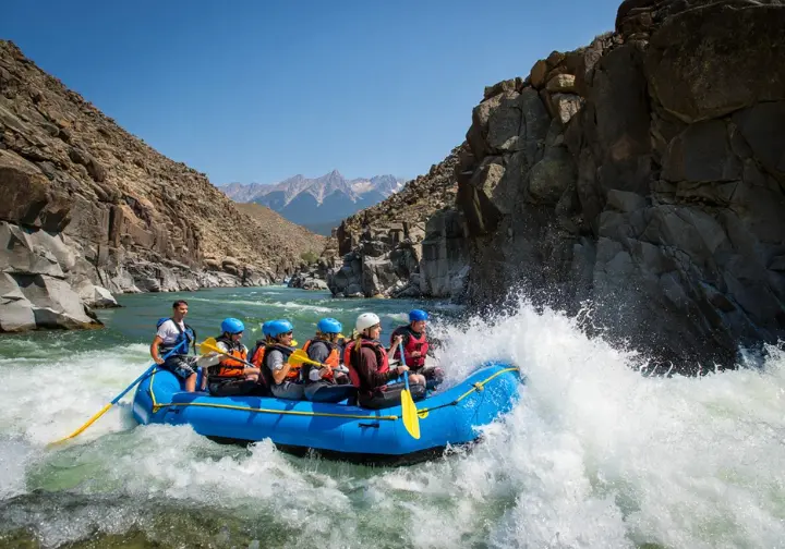 Deep dive into Browns Canyon rafting: Scenic view of a raft in the granite canyon with Class III rapids and mountain backdrop.