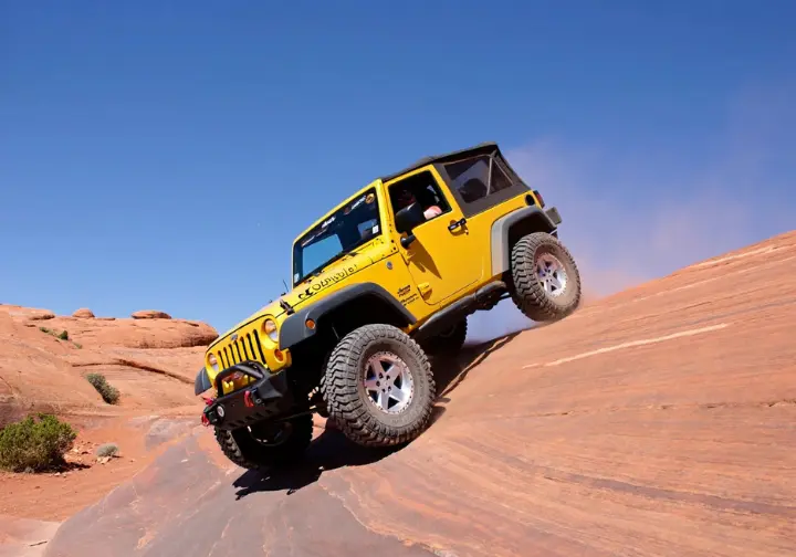 Go Moab off-roading: Jeep or UTV climbing a steep slickrock obstacle on the Hell's Revenge trail.