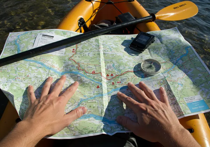 Planning your Green River kayaking Utah trip: hands pointing to route on map spread on kayak deck.