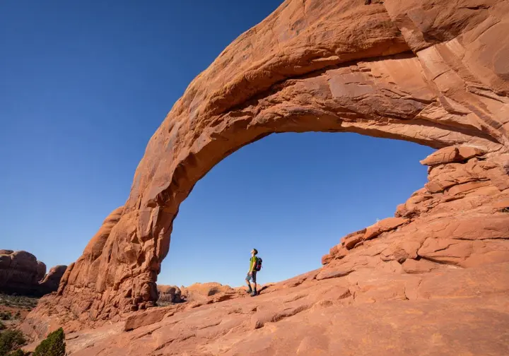 Hike outside the parks near Moab: Hiker admiring the massive Corona Arch.