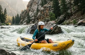 Best Inflatable Kayaks for Rivers We’d Run Paddler running an inflatable kayak through a river wave train on a sunny day