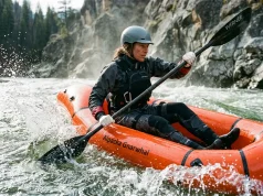 Best Packrafts for Every River and Trip 2026 Paddler in a whitewater packraft punching through a Class III wave train on a snowmelt river