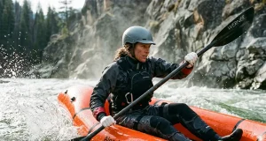 Best Packrafts for Every River and Trip 2026 Paddler in a whitewater packraft punching through a Class III wave train on a snowmelt river