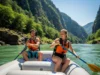 The J-Stroke: A Progressive Skill-Building Guide A fit young woman in a swimsuit and PFD guides a raft with a J-stroke while a male passenger rests, on a sunny river.
