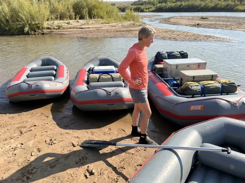 Three different length whitewater rafts lined up on a riverbank for size comparison
