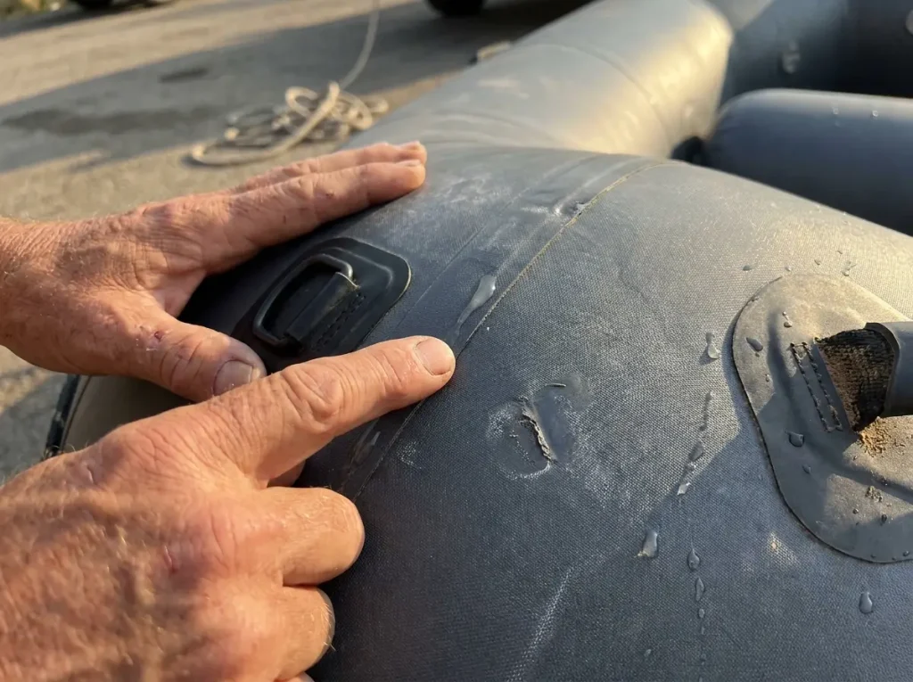 Close-up of a weathered Hypalon raft tube seam and D-ring patch showing material texture and glued construction