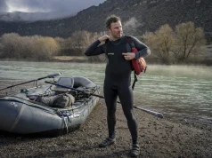 How to Layer for Cold Water Rafting Before You Swim Rafter layering up at a cold river put-in on a gray spring morning before launch