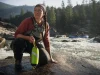 Best River Rescue Throw Bags and Why NFPA Is Overkill Rafter holding a high-vis green river rescue throw bag on a granite bank above a Class III rapid