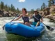 Rafting Paddle Repair: From Workshop to Riverbank Fixes A fit young couple whitewater rafting in the sun, paddling hard through a rapid in a full-body action shot.
