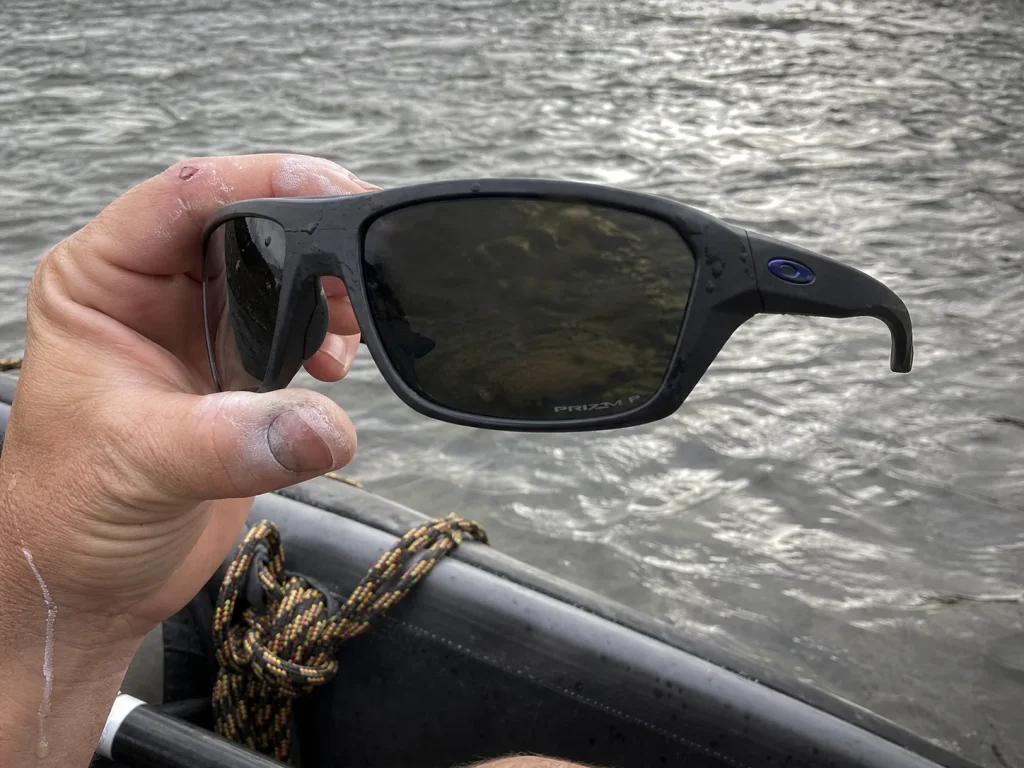 Close-up of polarized wraparound rafting sunglasses held up against the glare of a river surface