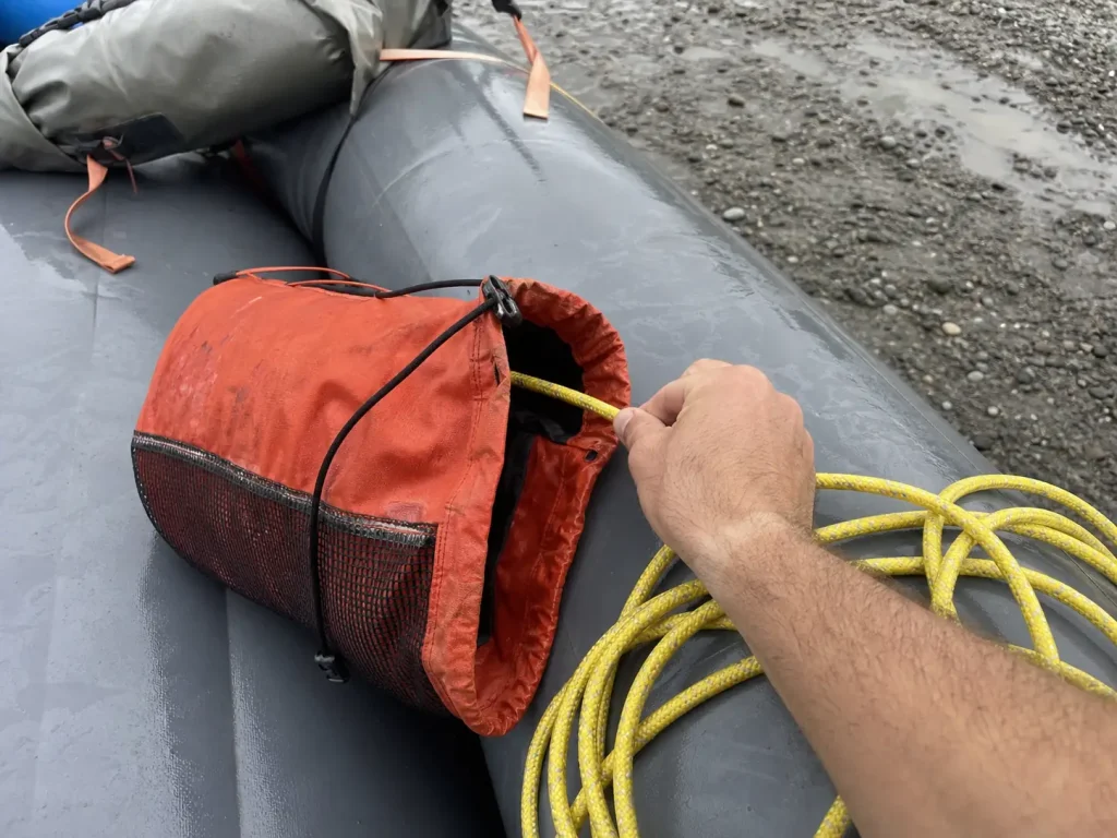 Close-up of a throw bag opened on a raft tube with the rescue rope pulled out beside it