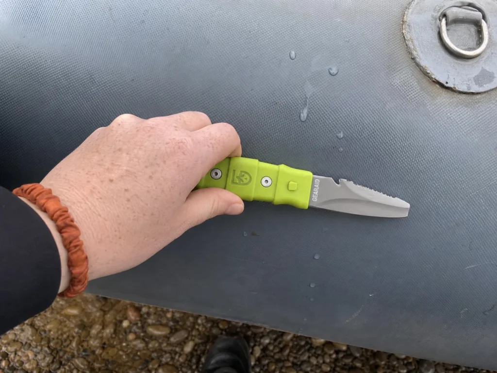 Blunt tip of a Gear Aid AKUA river knife held flat against an inflated raft tube