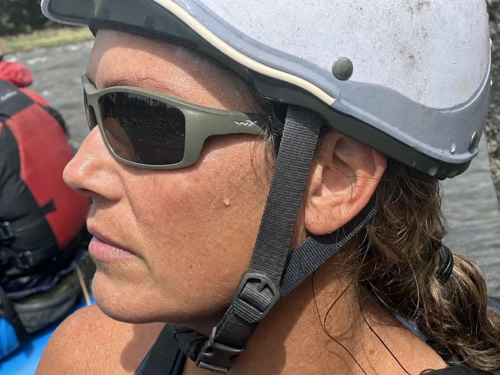 Side profile of a rafter in a helmet showing thin-armed sport sunglasses sitting flush under the strap