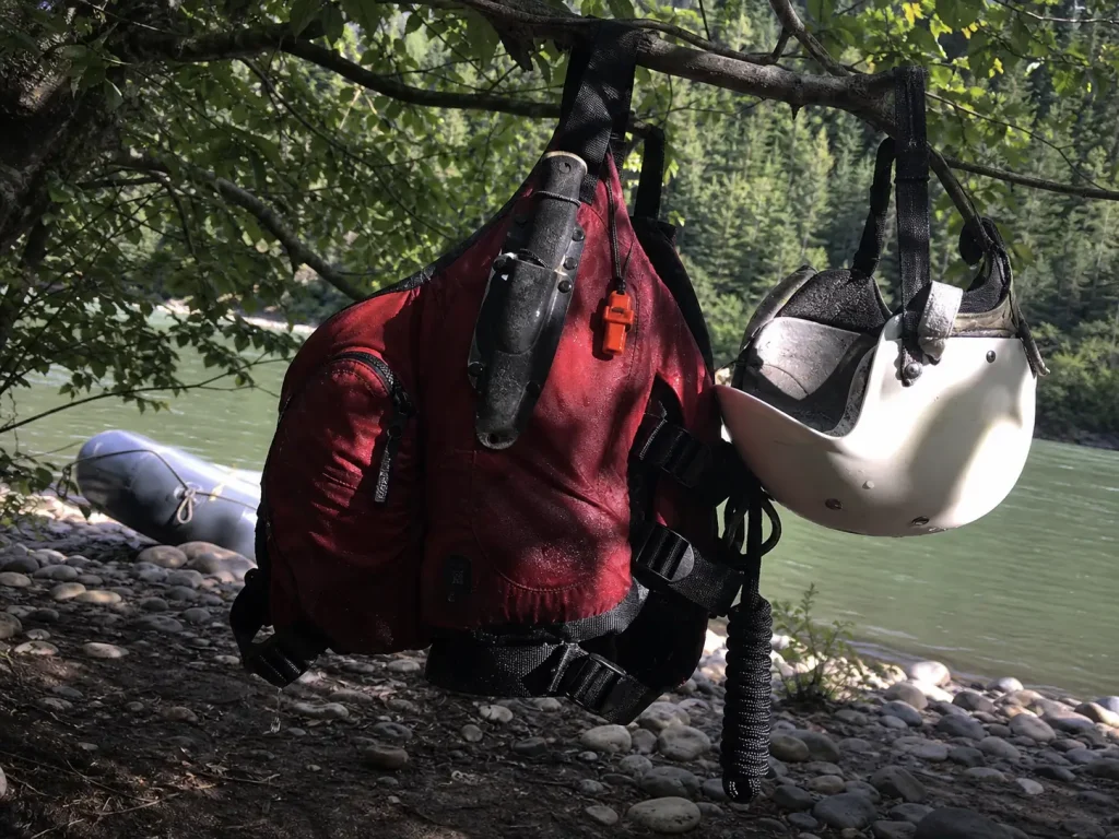 River knife, whistle and helmet hanging with a PFD — the safety gear around the river rescue kit