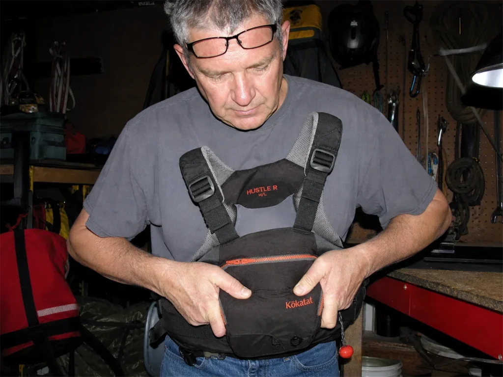 Squeezing the foam of a faded Kokatat rescue PFD in a garage to test whether it still springs back