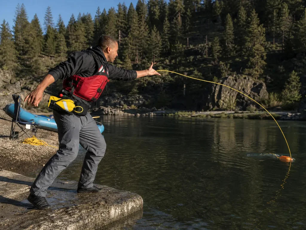 Boater throwing a rescue rope from a rock bank during throw bag practice on flat water