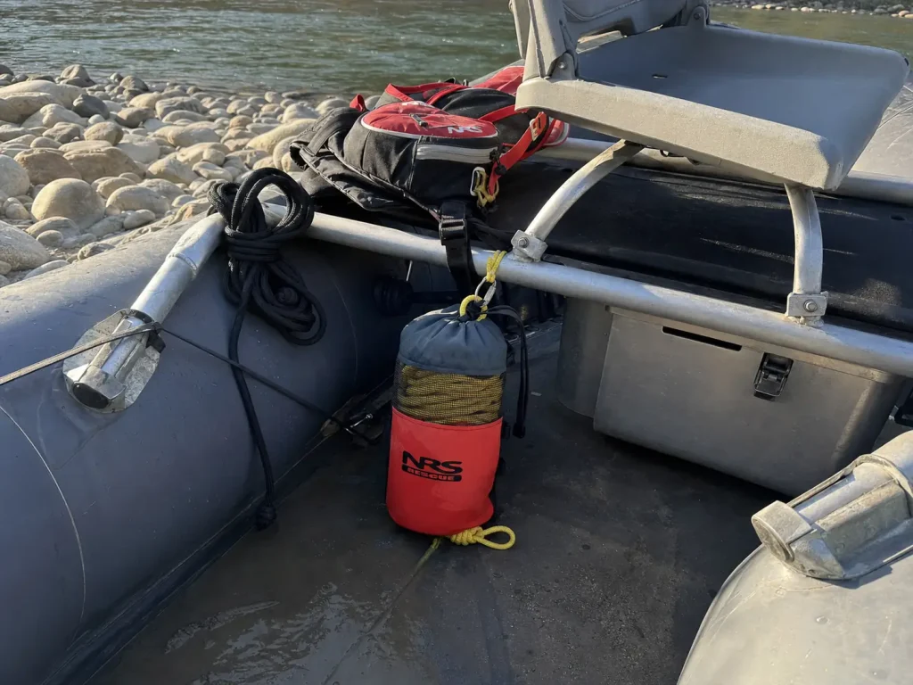 Throw bag rigged inside a raft frame where a river rescue kit rides on the boat, not on the body