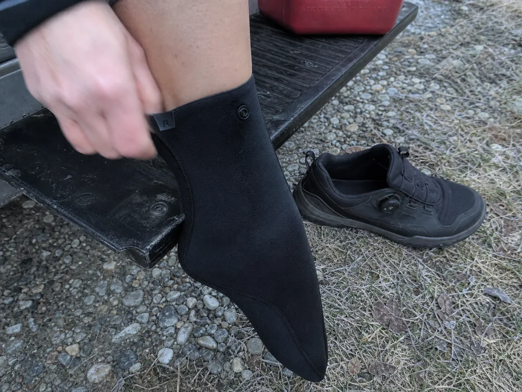 Pulling on an NRS HydroSkin neoprene wetsock before a cold spring-runoff rafting day