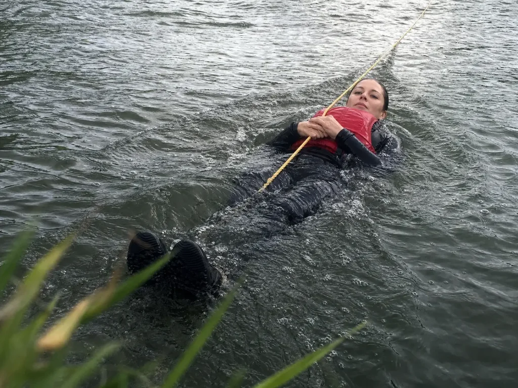 Swimmer on their back holding a rescue rope over one shoulder in the correct throw bag position