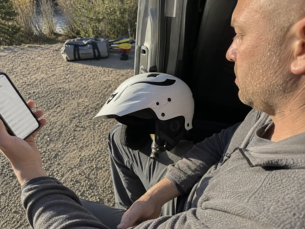 Paddler comparing a Sweet Protection Rocker helmet against helmet star ratings on a phone