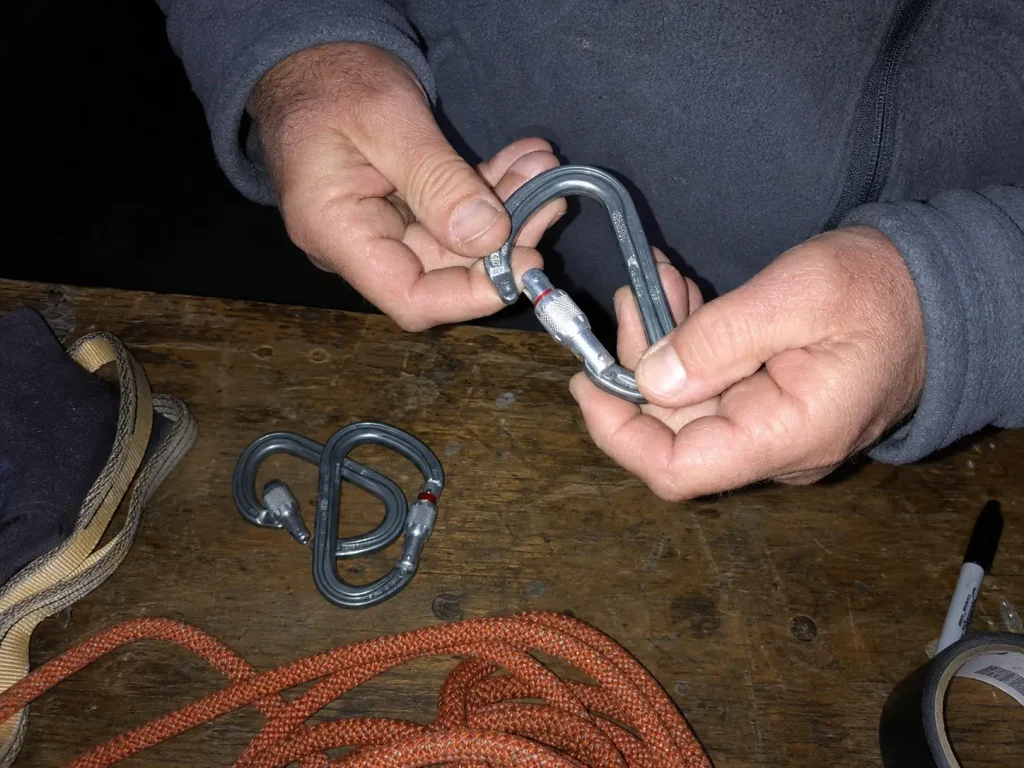 Preseason inspection of carabiners and rope from a river rescue kit on a garage workbench