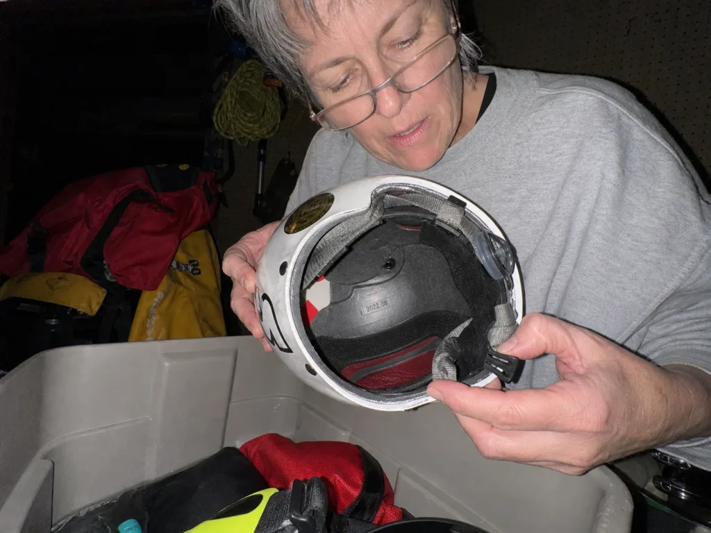 Checking the manufacture date stamp inside an old rafting helmet during an off-season gear audit