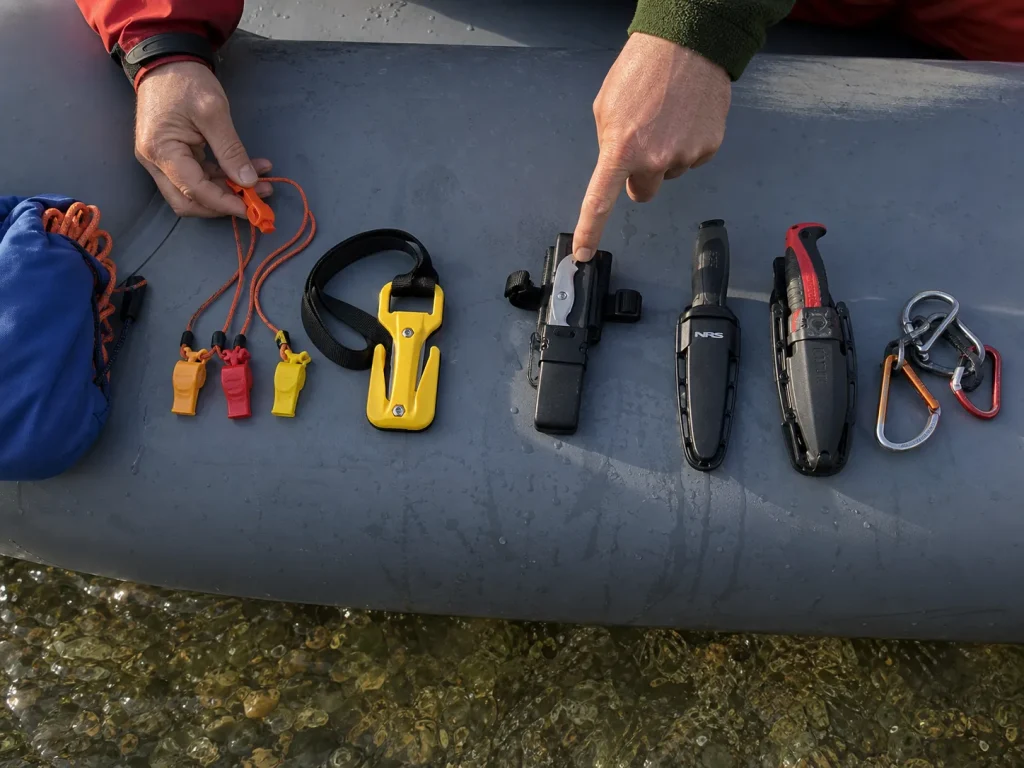 Crew safety gear laid out on a raft tube for a pre-launch check, including an Eezycut Trilobite