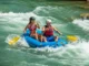 Mastering the Downstream V: A Foundational Rafting Skill A fit young couple in a raft navigate a whitewater rapid, following the clear path of a downstream V.