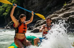 Gauley River Rafting Guide: Upper vs. Lower & Outfitters A man and woman in a full-body view, wearing swimwear, celebrate excitedly while whitewater rafting through a rocky river canyon.