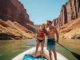 The Grand Canyon Rafting Matrix: Trip Intensity & Cost A full-body shot of an athletic young couple on a raft in the Grand Canyon, enjoying the sunny weather and spectacular scenery.