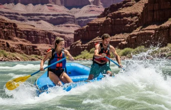 Grand Canyon Itinerary Mapped: Rafting by Skill Level Full-body shot of a young couple rafting through a major rapid in the Grand Canyon, with towering red rock walls in the background.