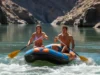 Laminar vs Turbulent Flow: A Rafter’s Guide to River Reading A fit couple in their late 20s rafting on a sunny river, moving from a calm, glassy section of water towards turbulent whitewater rapids ahead.