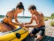 Raft Repair Kits: From Day Trips to Expeditions A fit couple in their late 20s works together to repair an inflatable raft on a sunny riverbank.