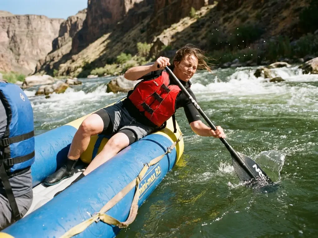Paddler in a small 18-inch mini-max raft reaching to the water showing how tube size affects paddle length