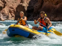 Decoding River Features: A Rafter’s Safety Guide A full-body shot of a young man and woman in a raft, safely navigating a whitewater rapid by reading the river's currents.