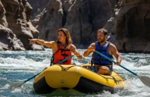 The Rafter’s CFS Impact Scale: Reading River Flows A full-body landscape shot of an athletic couple in their late 20s in a raft, studying the whitewater ahead on a sunny day.