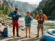 Rafting Gear Checklist by River Class 1 to 5 Rafters in full safety gear at river put-in checking PFD and helmet fit before Class III rapids