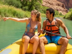 The River Runner’s Toolkit for Active Conservation A fit young couple in swimwear on a raft, looking at the healthy, green shoreline of a scenic river canyon on a sunny day.