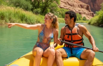 The River Runner’s Toolkit for Active Conservation A fit young couple in swimwear on a raft, looking at the healthy, green shoreline of a scenic river canyon on a sunny day.