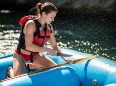River Knife Review: Cut Tests, Sheath Security & Top Picks A full-body shot of a fit young woman in a bikini and life jacket using a river knife to cut webbing on a whitewater raft.