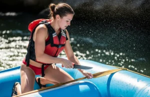 River Knife Review: Cut Tests, Sheath Security & Top Picks A full-body shot of a fit young woman in a bikini and life jacket using a river knife to cut webbing on a whitewater raft.