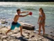 Using a Throw Bag: From Basic Toss to River Rescue A fit man in his late 20s demonstrates how to use a throw bag on a sunny riverbank while a woman in a bikini watches.