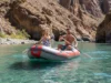 South America’s Top Rivers: A Rafting Guide by Class An attractive couple in their late 20s rafting on a turquoise river in a massive South American canyon, captured in a wide-angle smartphone photo.