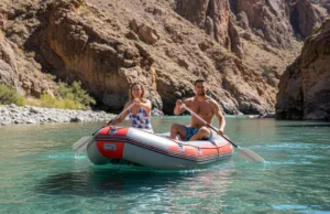 South America’s Top Rivers: A Rafting Guide by Class An attractive couple in their late 20s rafting on a turquoise river in a massive South American canyon, captured in a wide-angle smartphone photo.