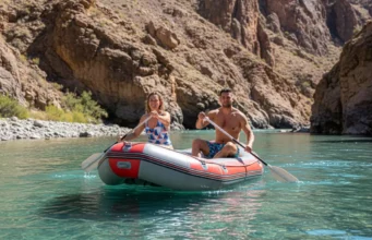 South America’s Top Rivers: A Rafting Guide by Class An attractive couple in their late 20s rafting on a turquoise river in a massive South American canyon, captured in a wide-angle smartphone photo.